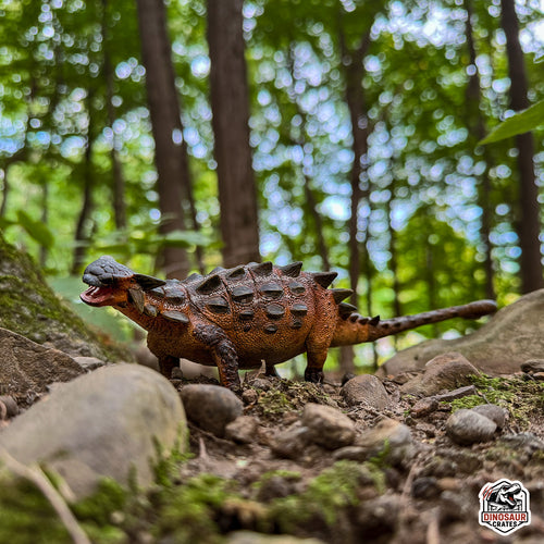 EoFauna Ankylosaurus Dinosaur toy in a forest setting with trees and rocks in the background